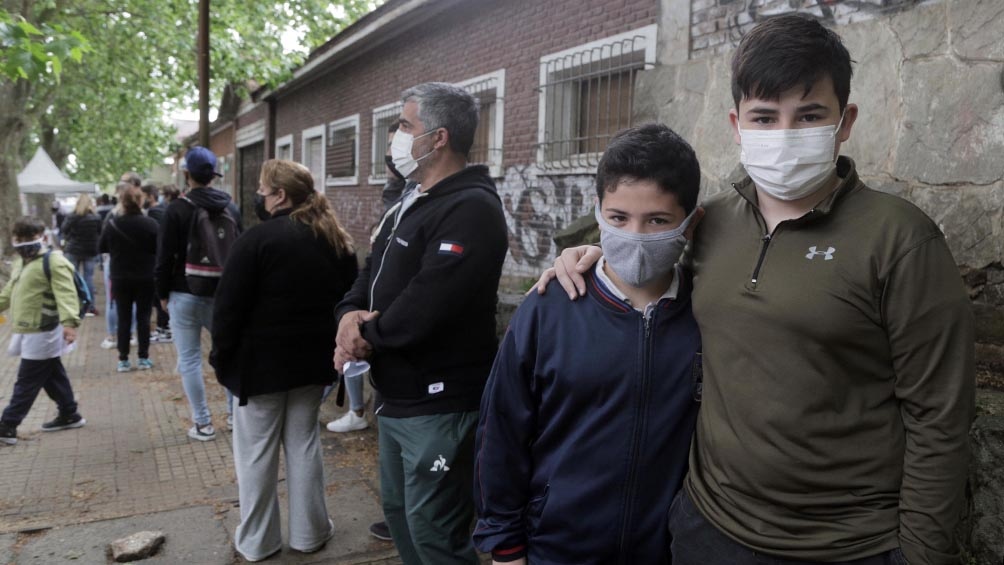 Agustín (10) y Nicolás (15) esperan en el Hipódromo de La Plata ingresar al predio para su vacunación. (Foto Leo Vaca)